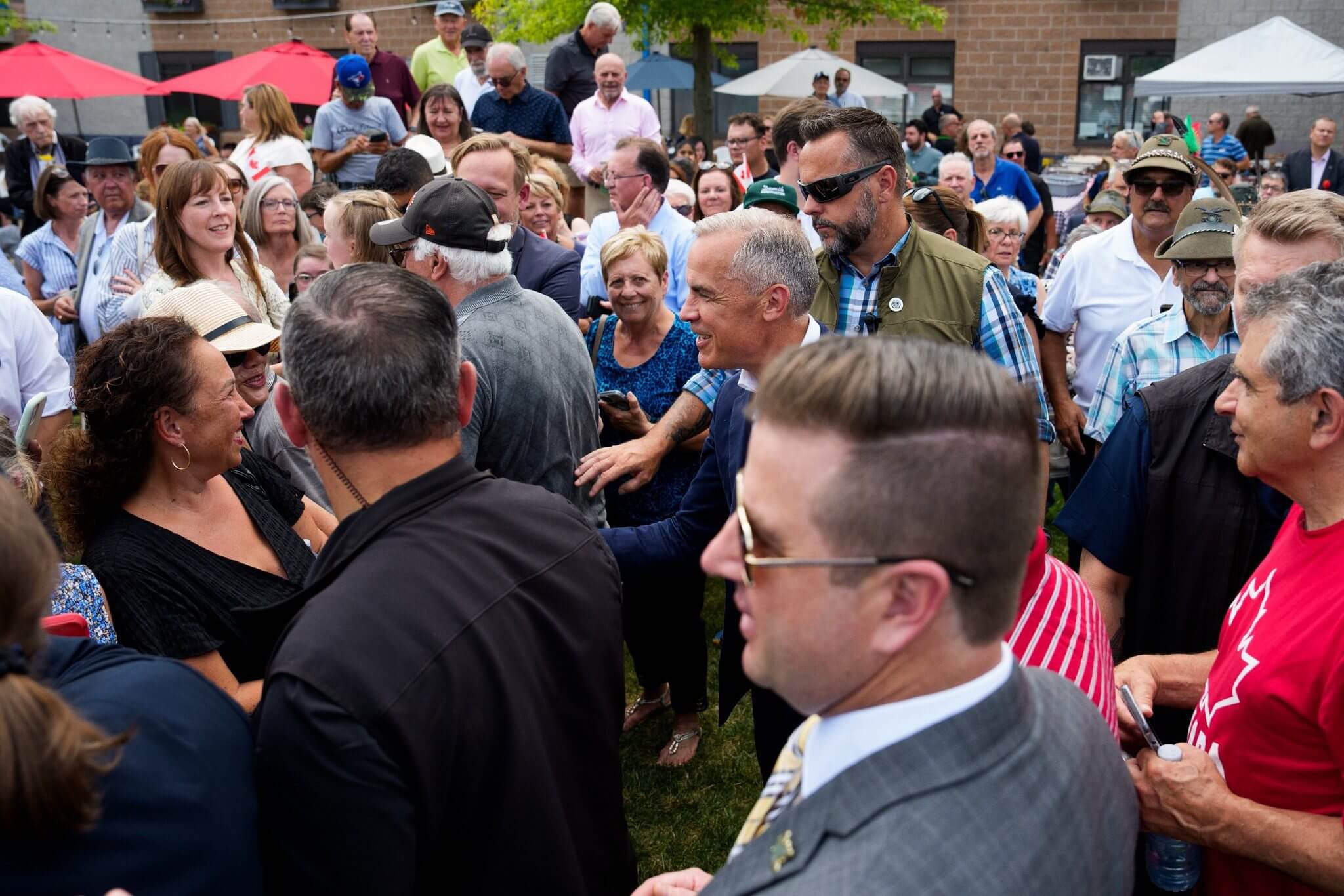 Crowd gathered outdoors with people dressed formally and casually.