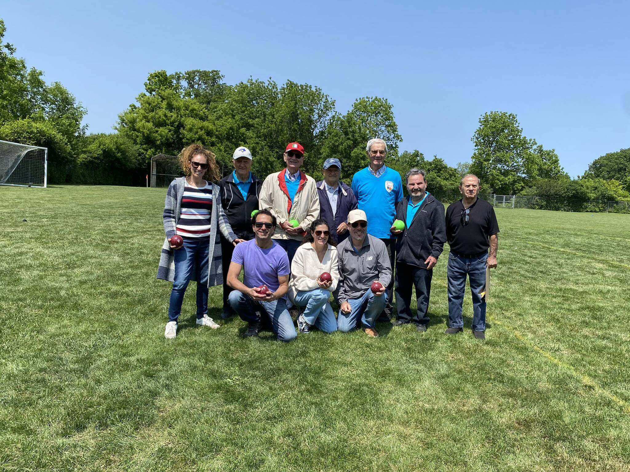 A group of ten people posing outdoors on a sunny day.