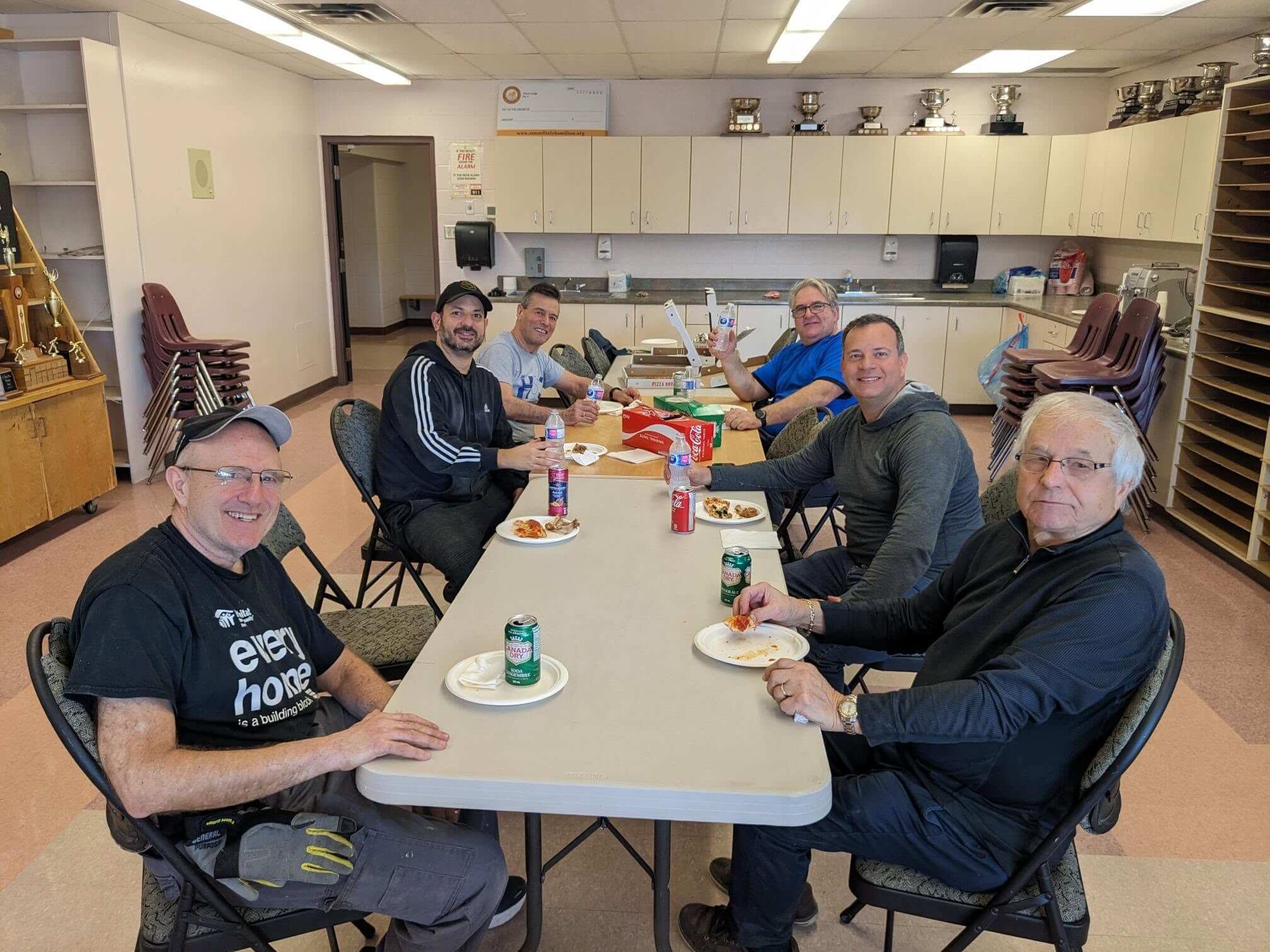 Group of men enjoying a meal together around a long table.