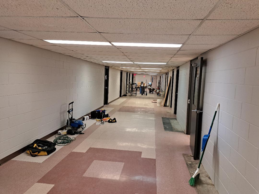 A long hallway with cleaning equipment and people at the far end.