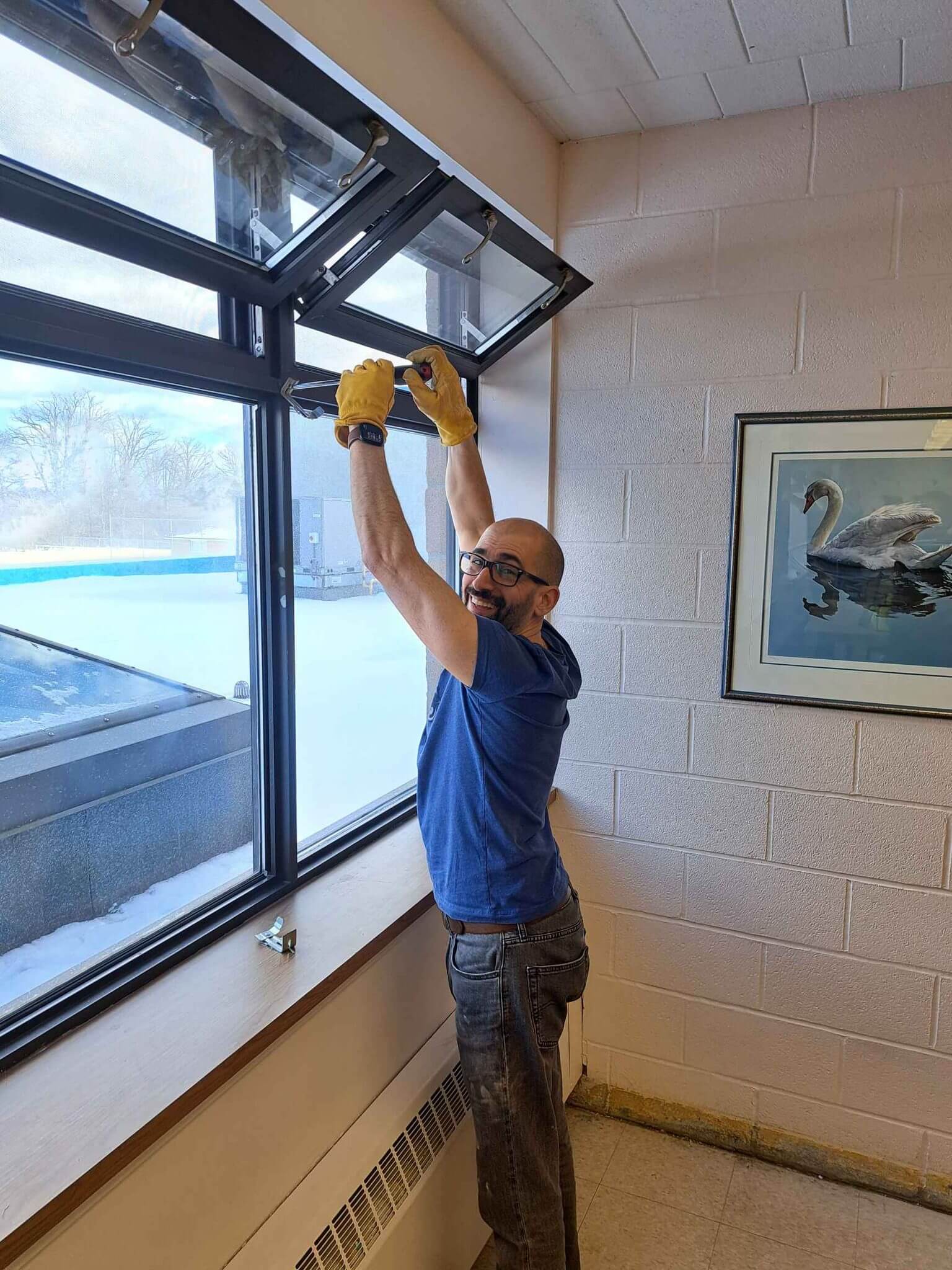 Man installing a ceiling light fixture near a window in a room.