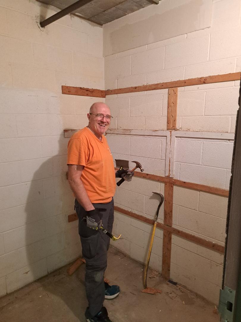 Man working on wall renovation in a room.