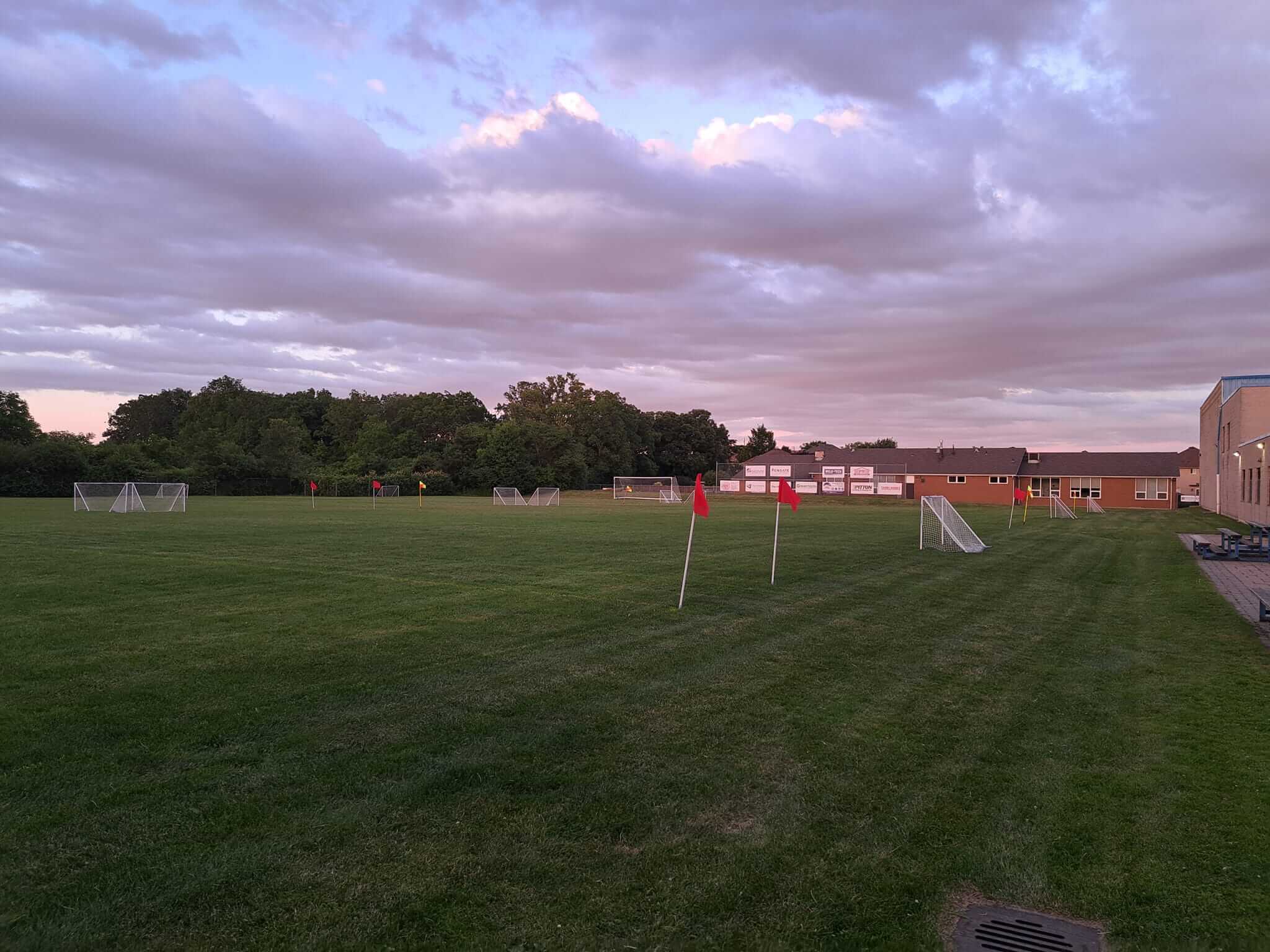 A peaceful soccer field under a cloudy sky at dusk.