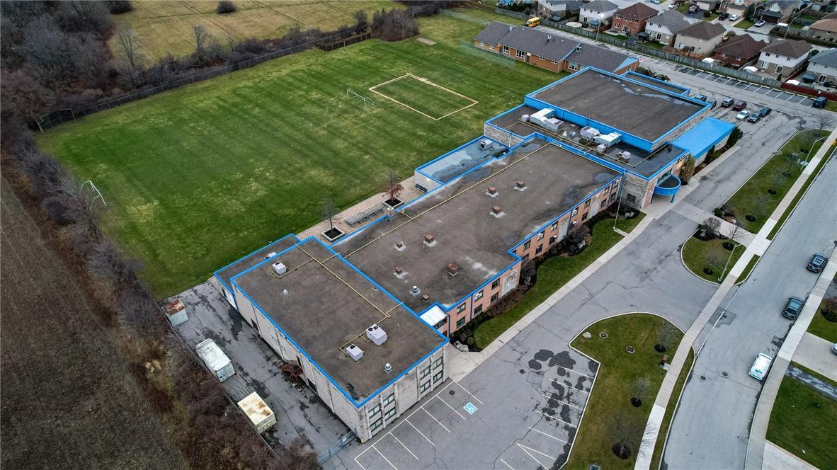 Aerial view of a school building next to sports fields and residential homes.