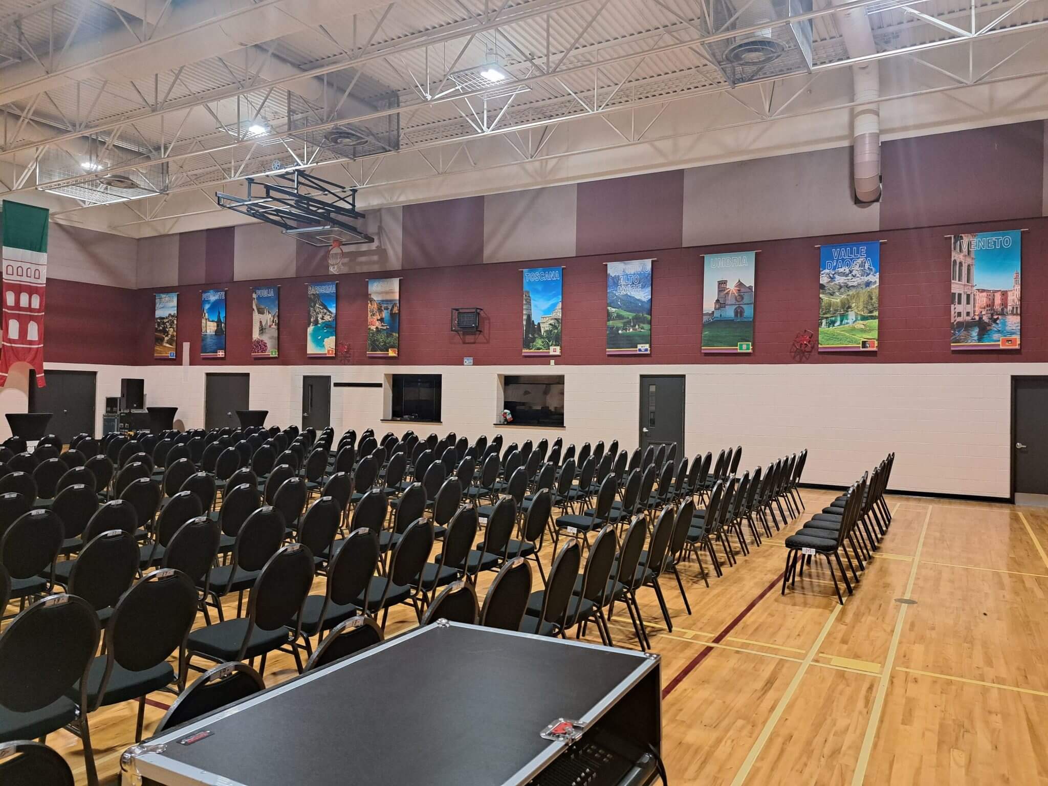 Empty gymnasium with rows of black chairs arranged for an event.