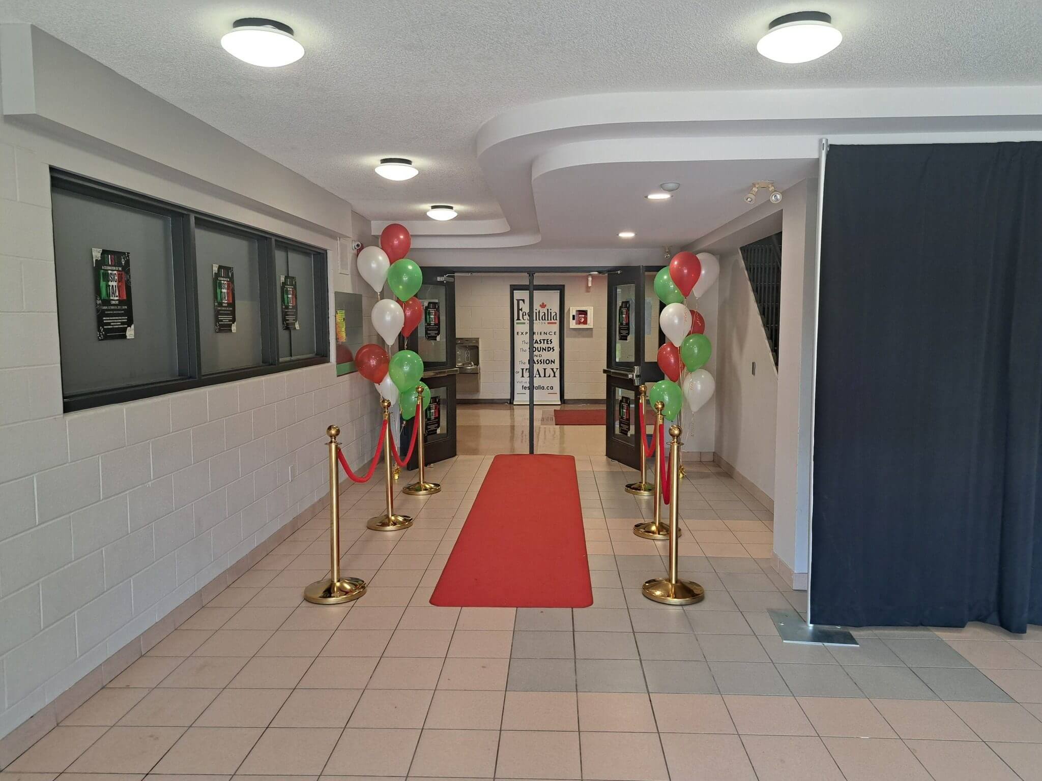 Red carpet and balloon decorations in a hallway for an event.