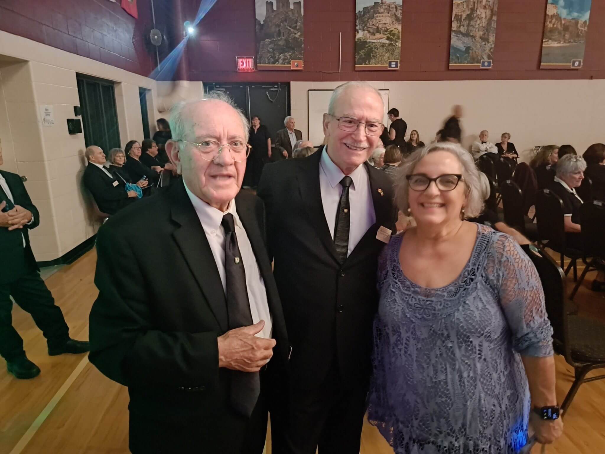 Three formally dressed individuals posing at an indoor event.