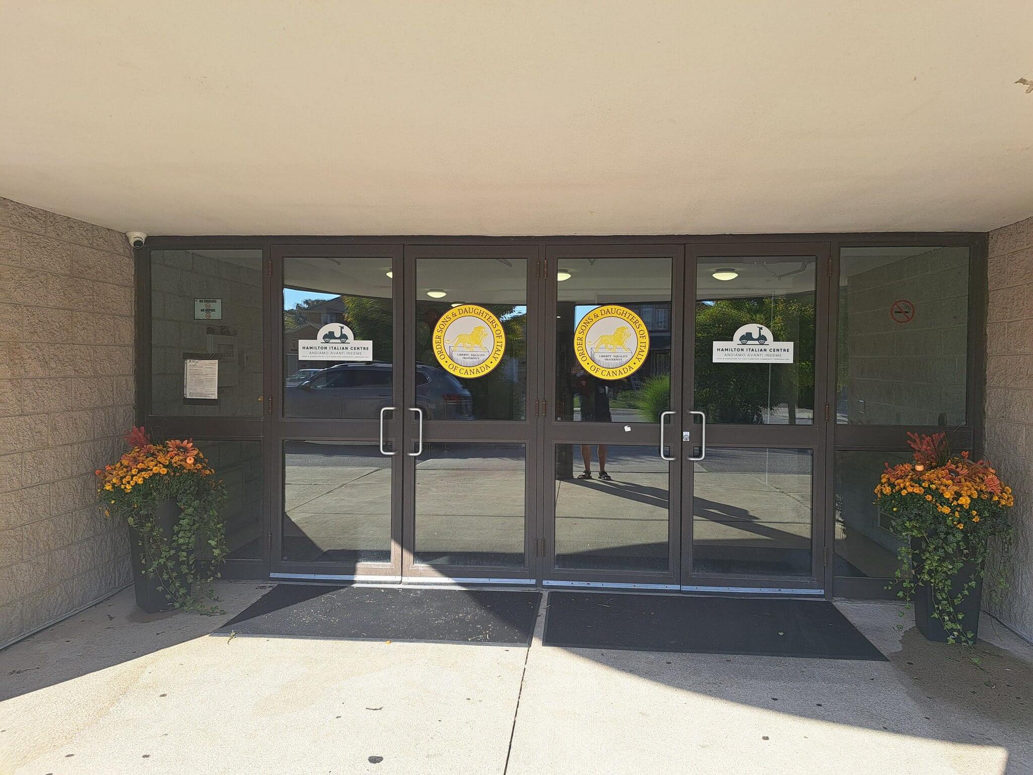 Main entrance doors of a school building with clocks and signs.