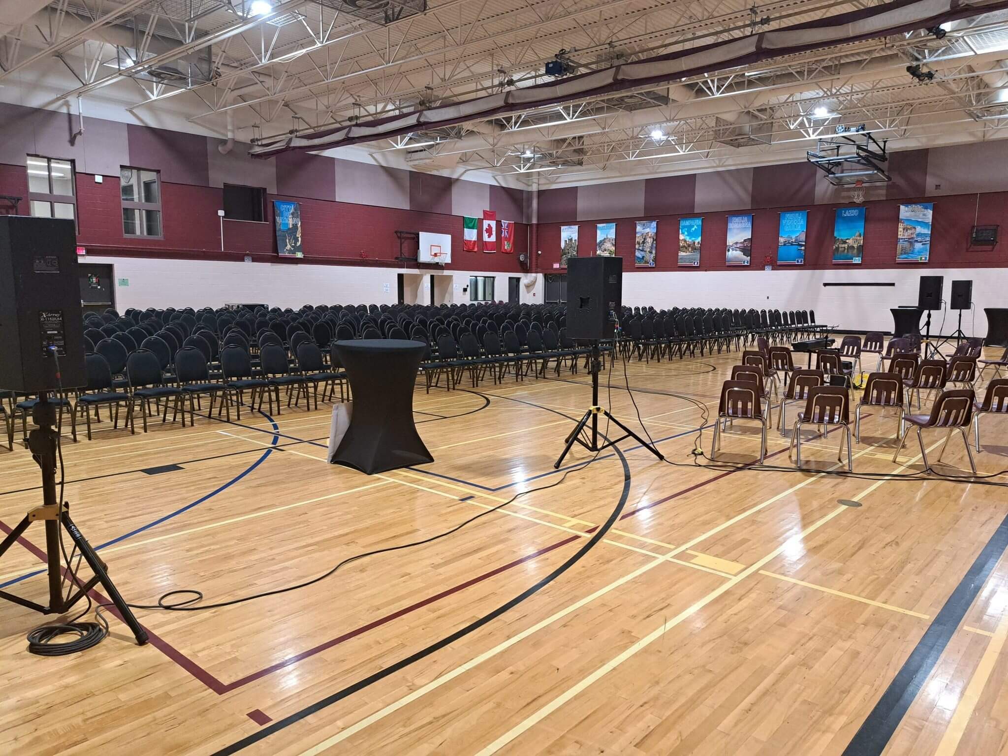 A gymnasium set up with chairs and microphones for an event.