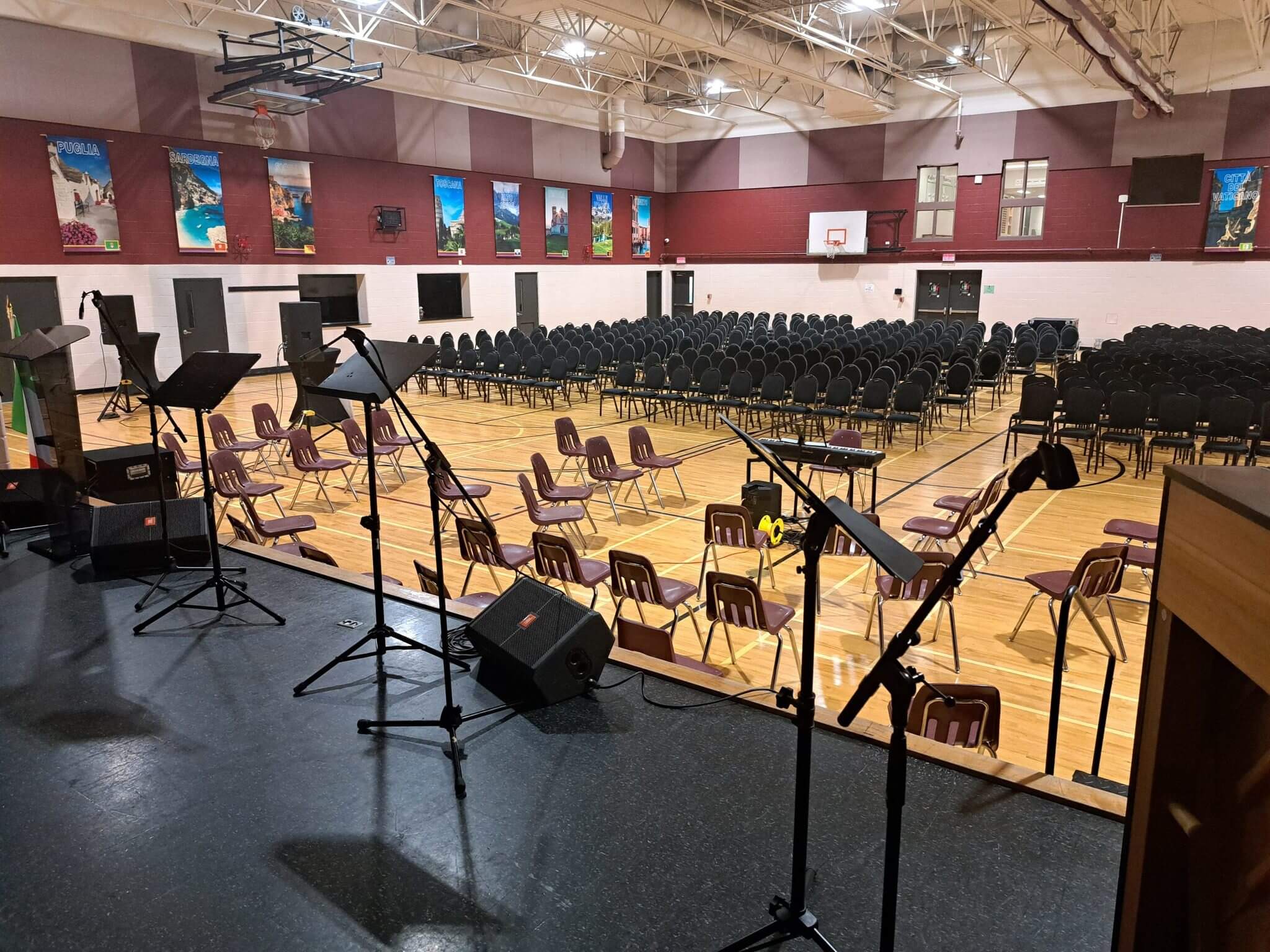 Empty gym set up with chairs and microphones for an event.