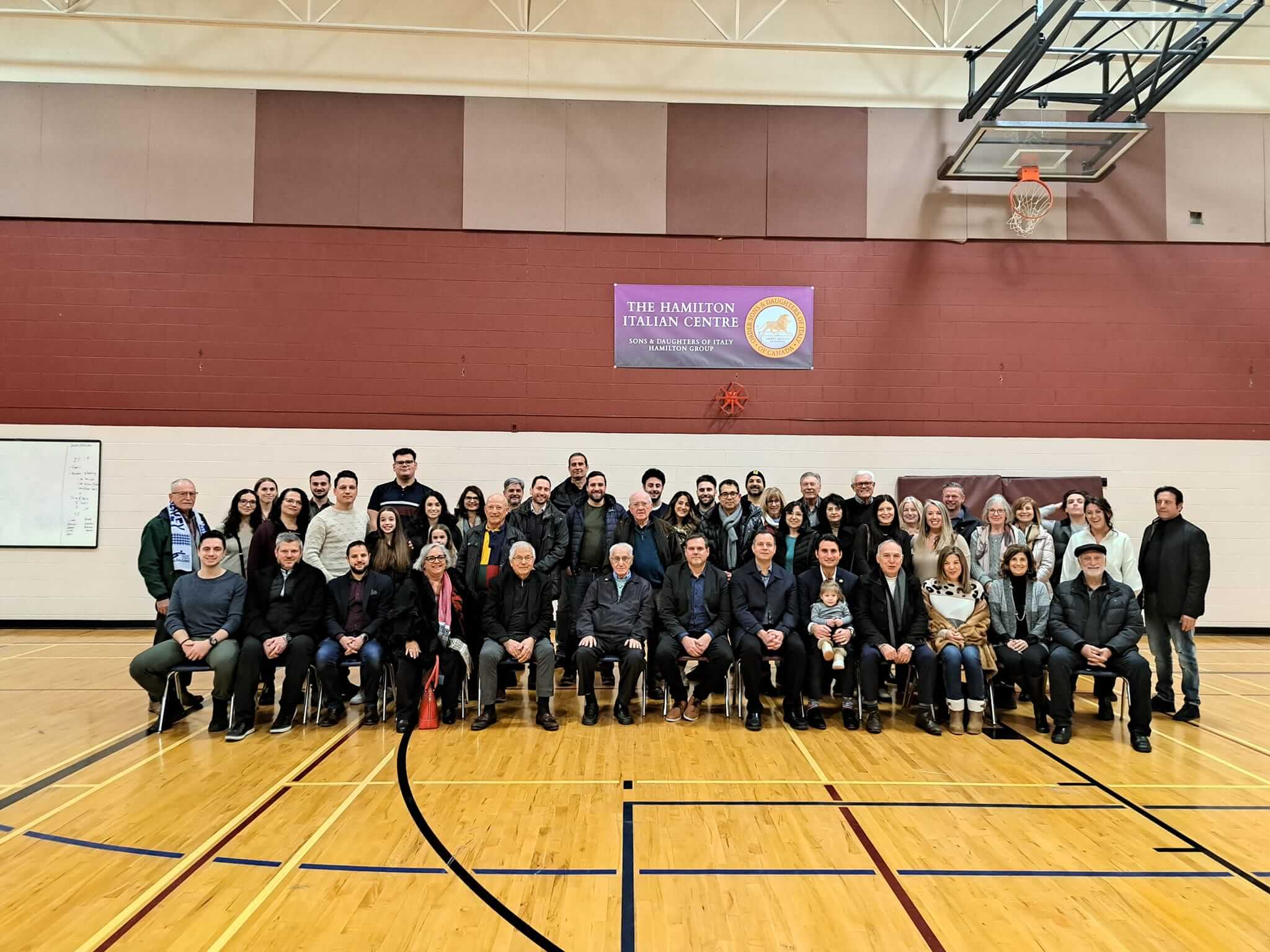 Group photo of people in a gymnasium with a basketball hoop.