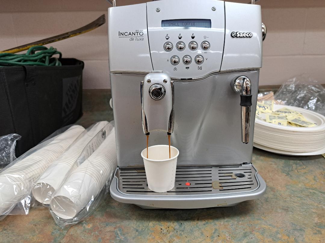 Saeco automatic espresso machine dispensing coffee into a paper cup.