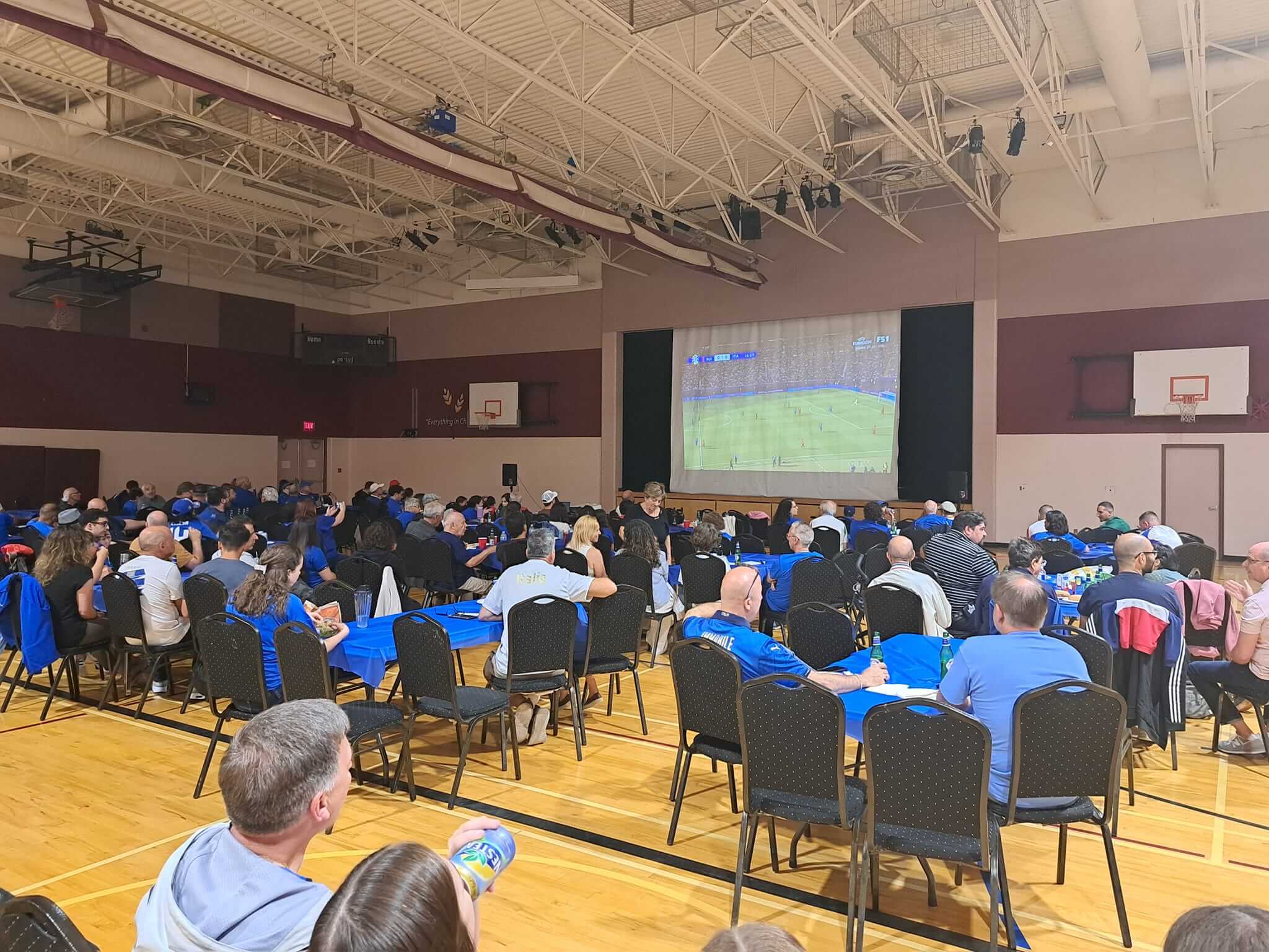Students watch a presentation in a school gymnasium.