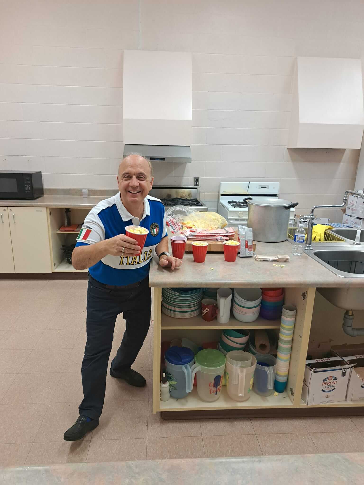 Man smiling in a kitchen holding a cup of yogurt.