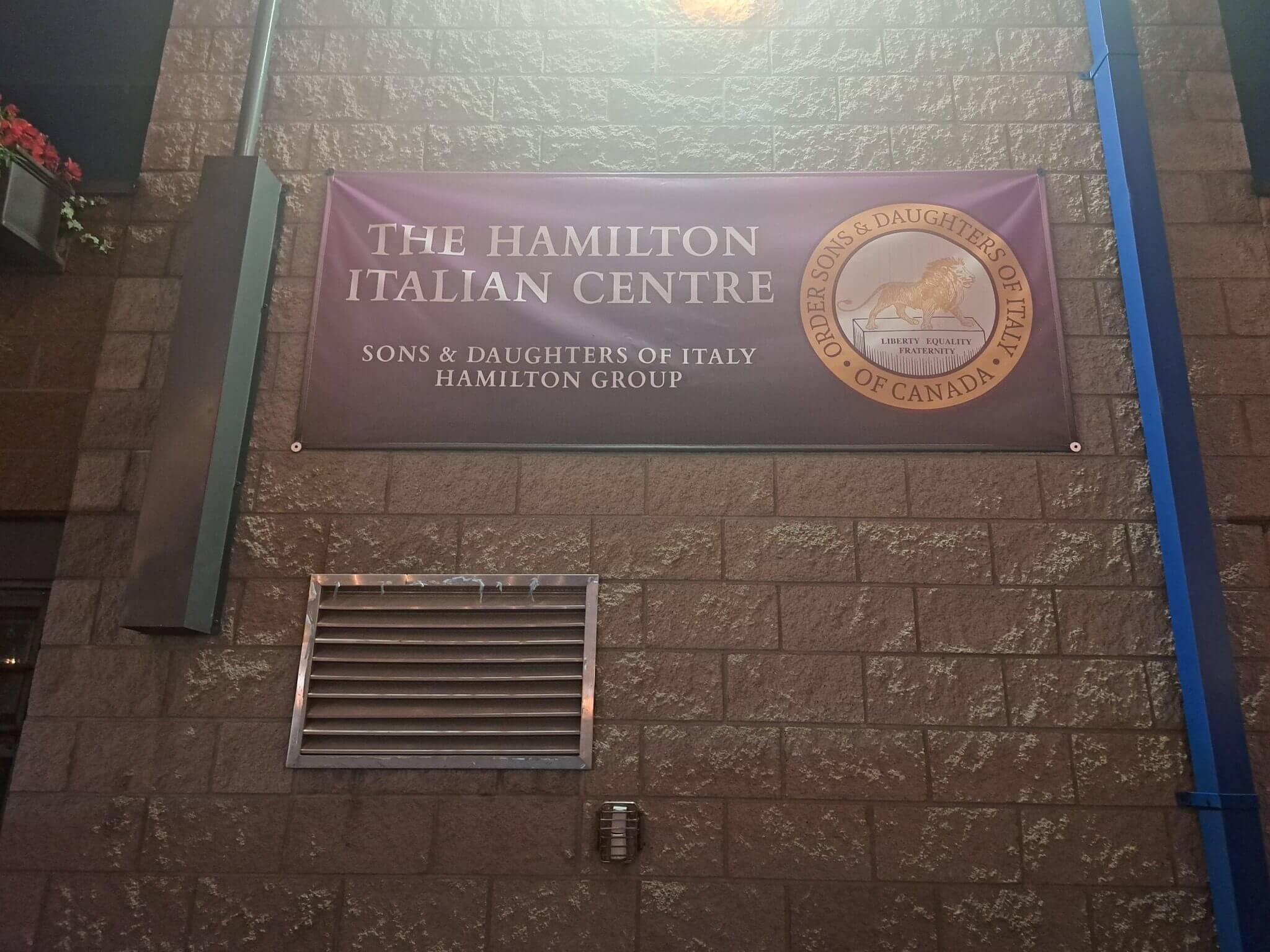 Sign for The Hamilton Talking Centre on a brick wall.
