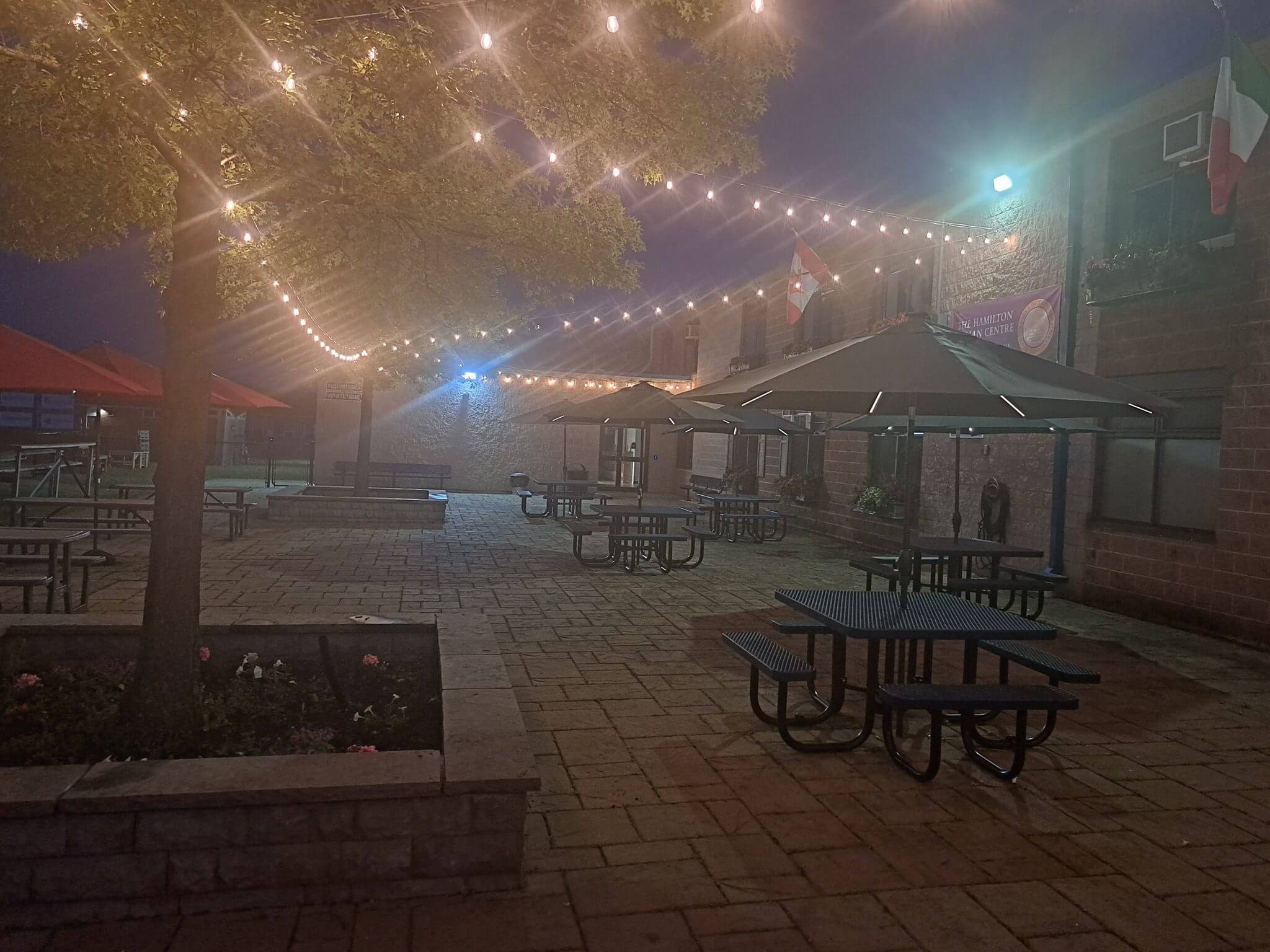 Outdoor patio with string lights and empty tables at night.