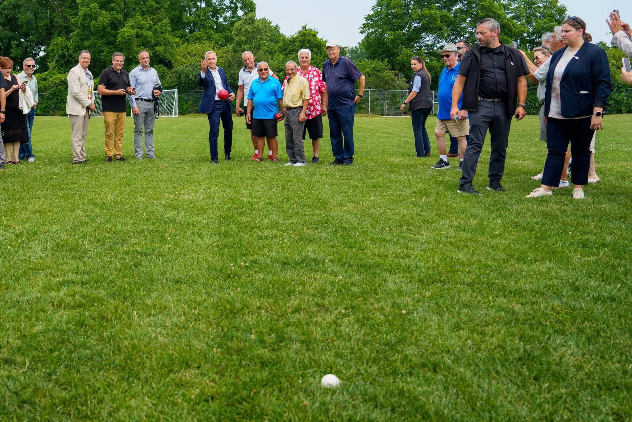 Group watching a golf ball on a grassy field during a game.