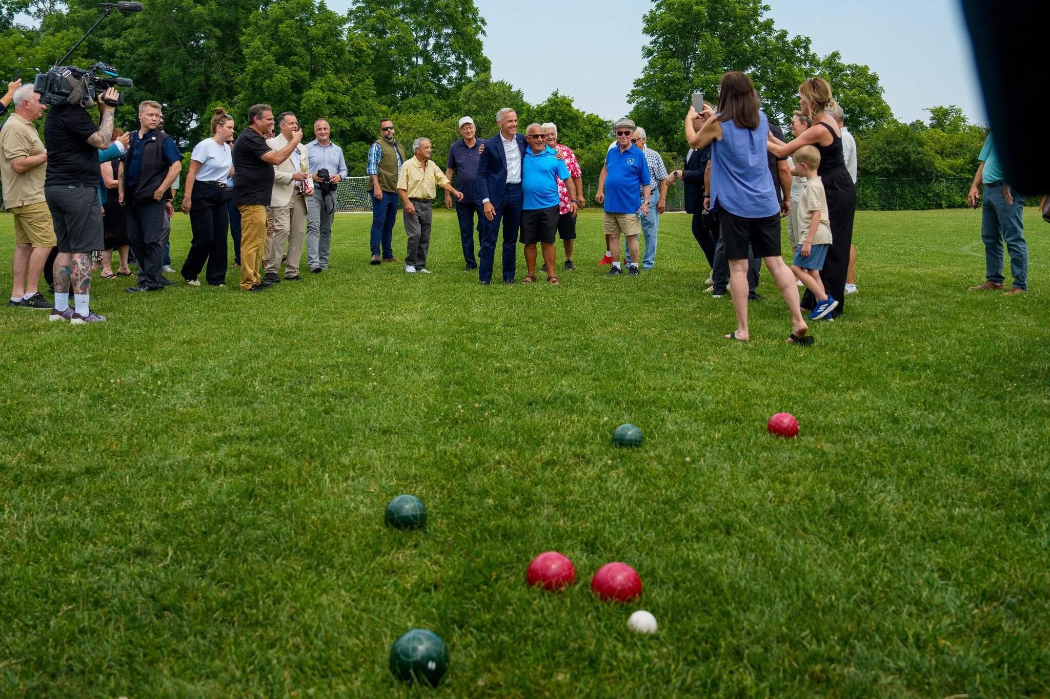 Group of people playing bocce ball outdoors on a grassy field.