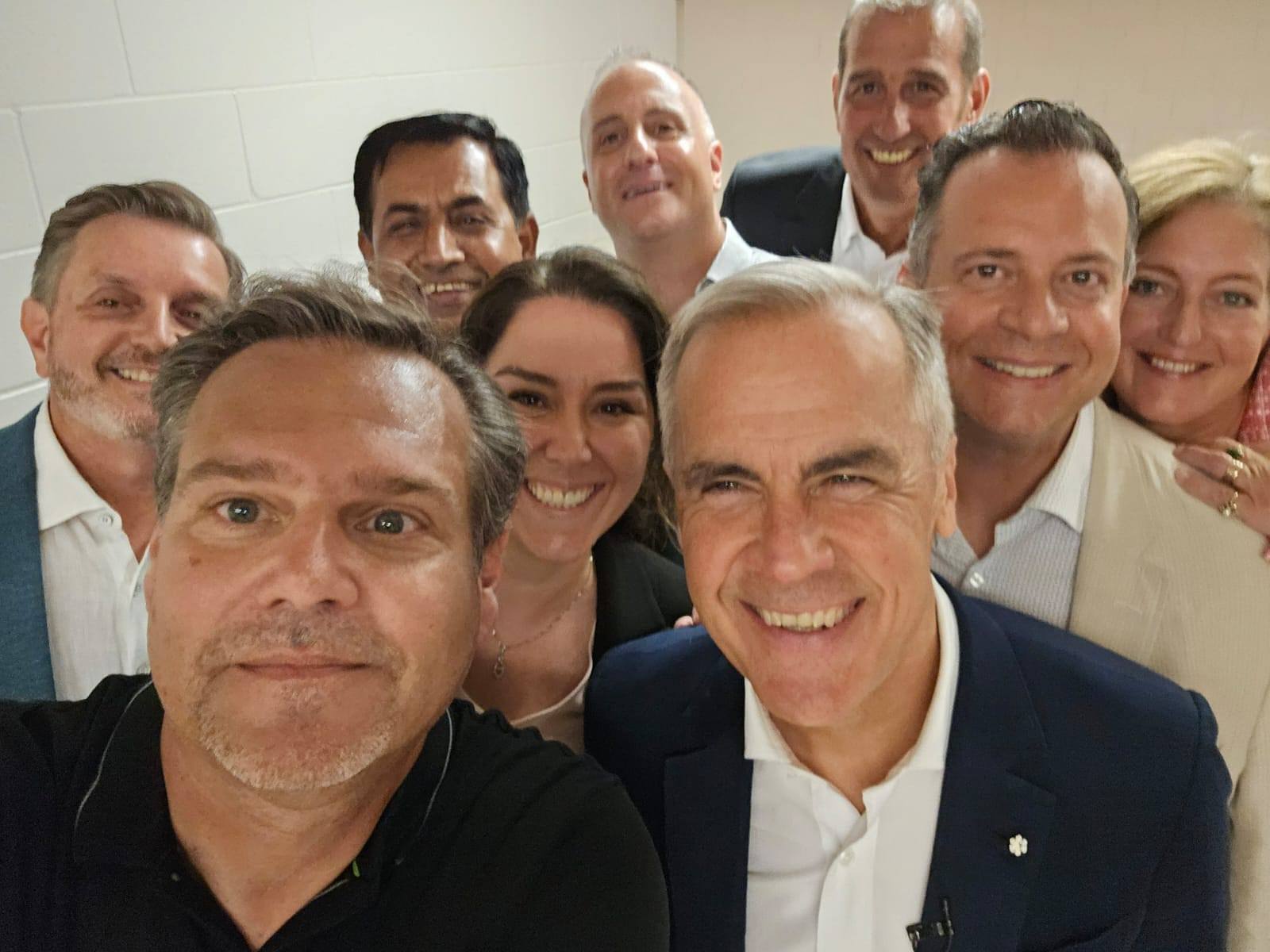 Group of people smiling for a selfie indoors.