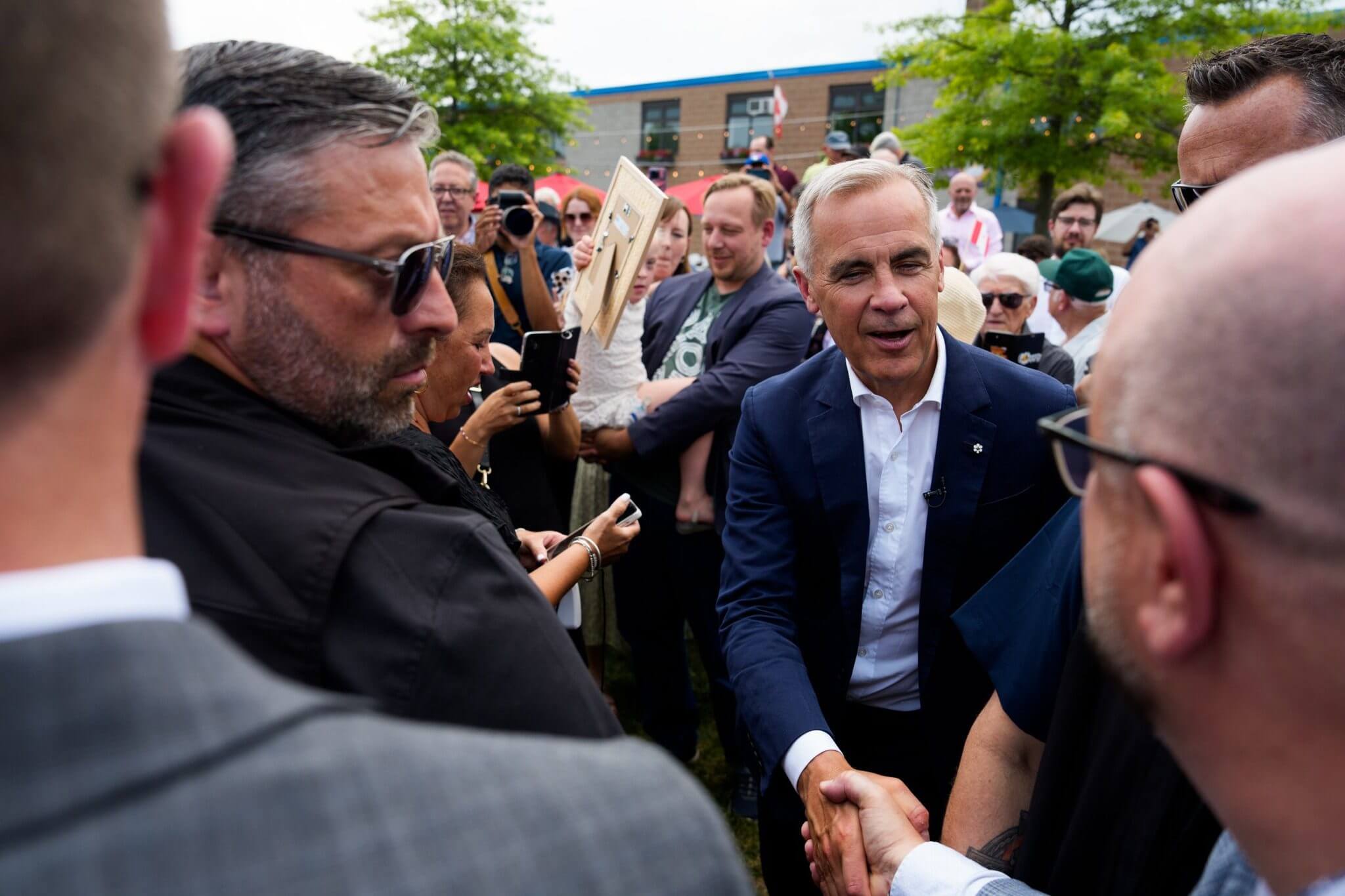 Politician shaking hands with supporters outdoors.