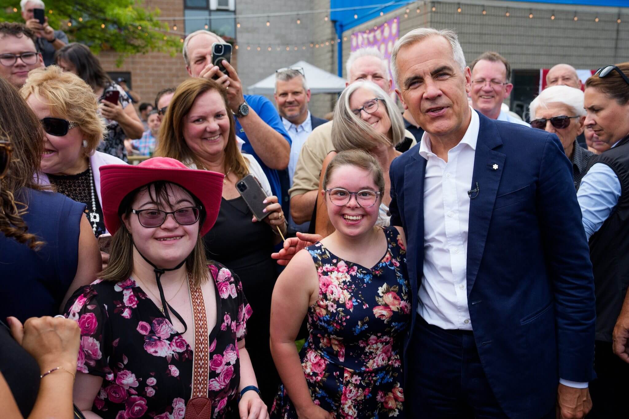 Group photo with a man in a suit and young women, one wearing a pink cowboy hat.