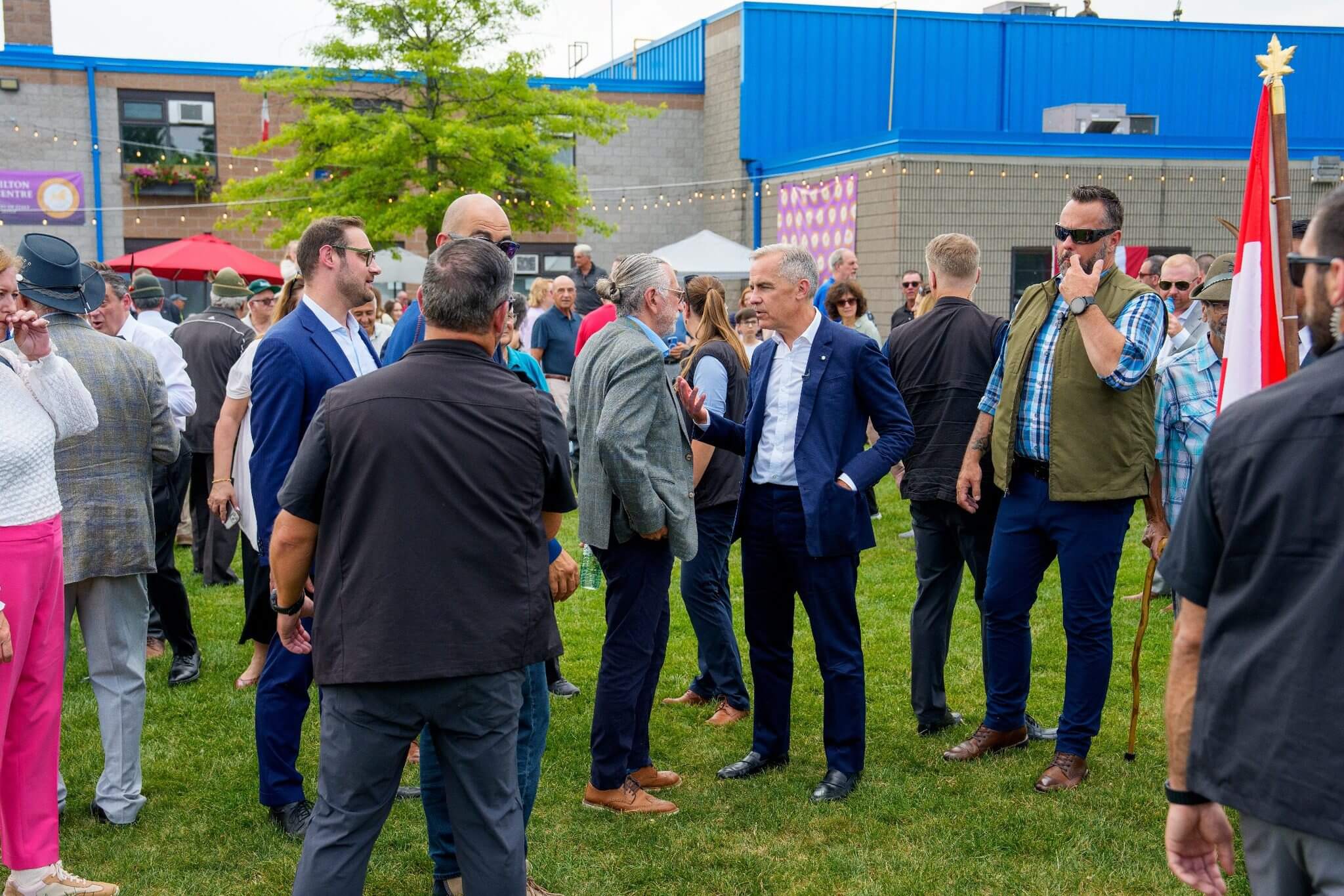 A group of men in business attire conversing outdoors on grass.