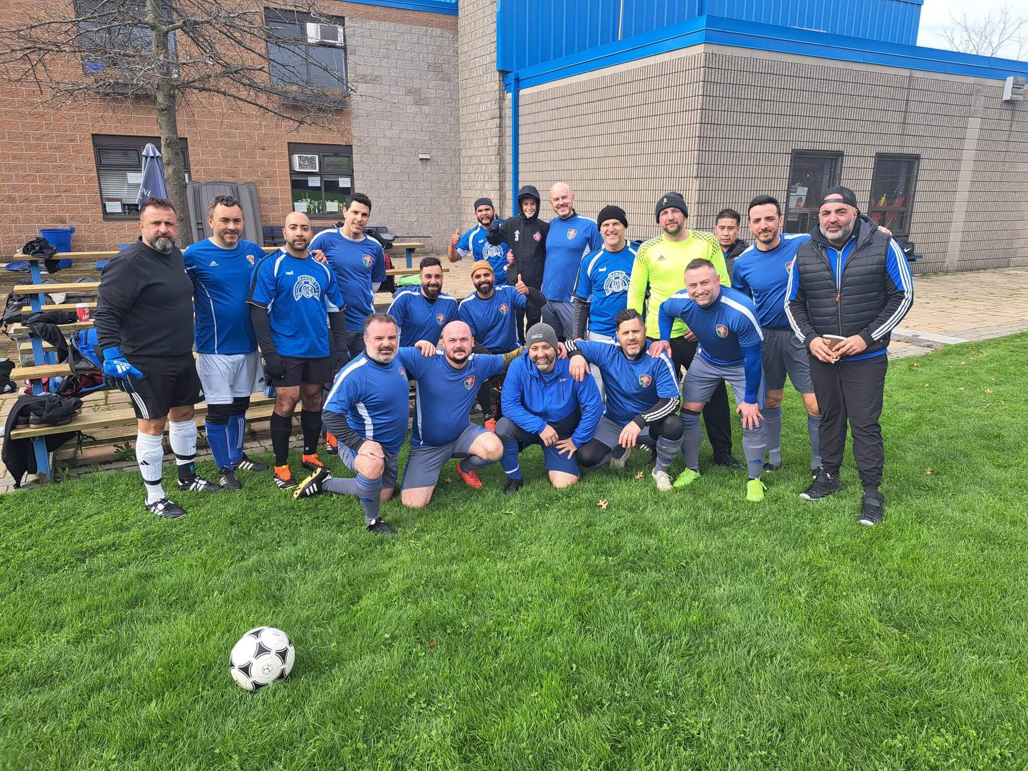 A group photo of a soccer team and coaches on a grassy field.