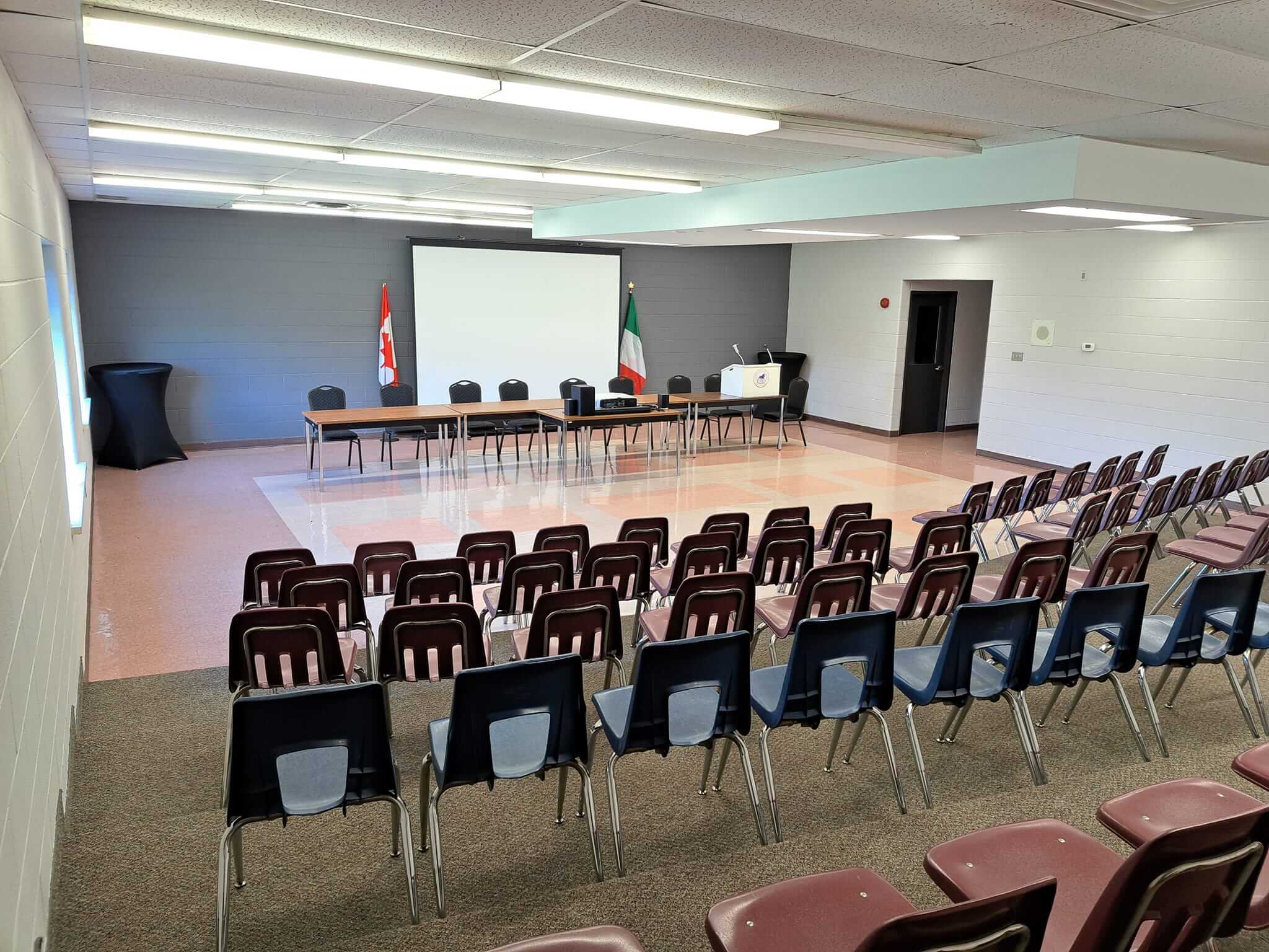 A conference room set up with chairs and tables facing a projector screen.