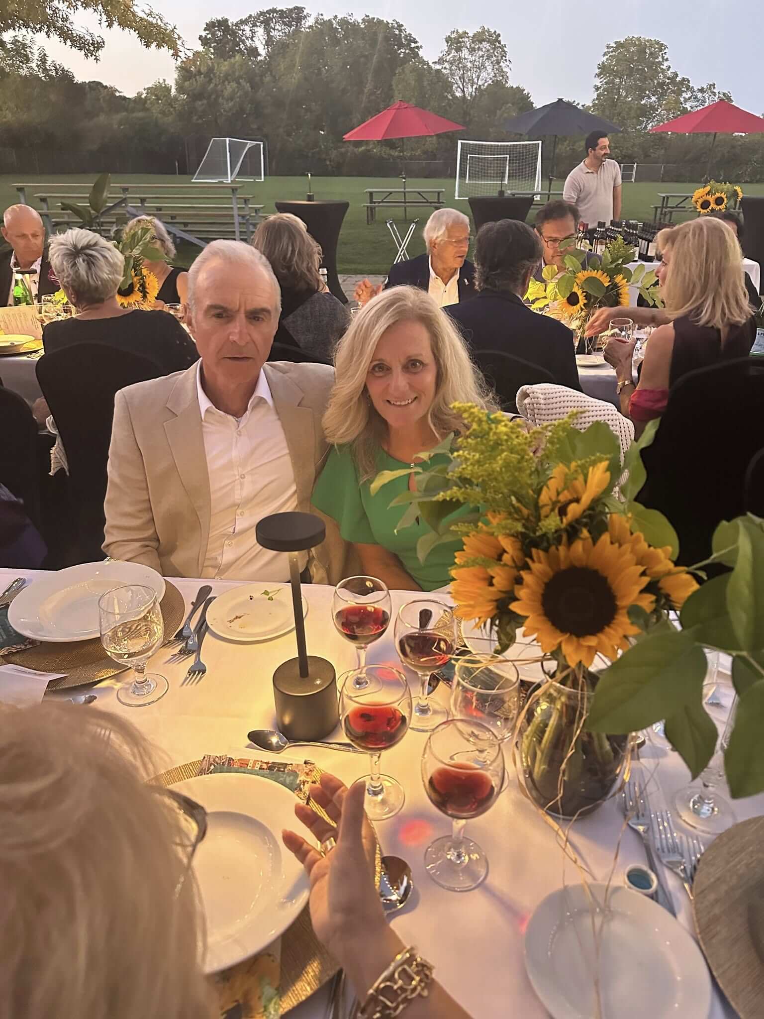 Couple enjoying an elegant outdoor dinner with sunflowers as centerpiece.