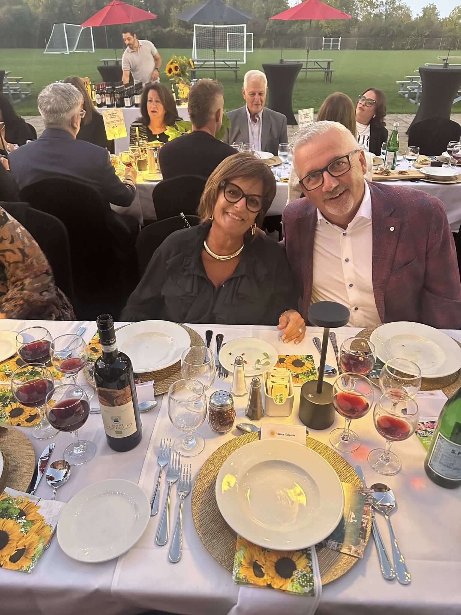 Elderly couple smiling at a formal dinner event with wine and elegant table settings.