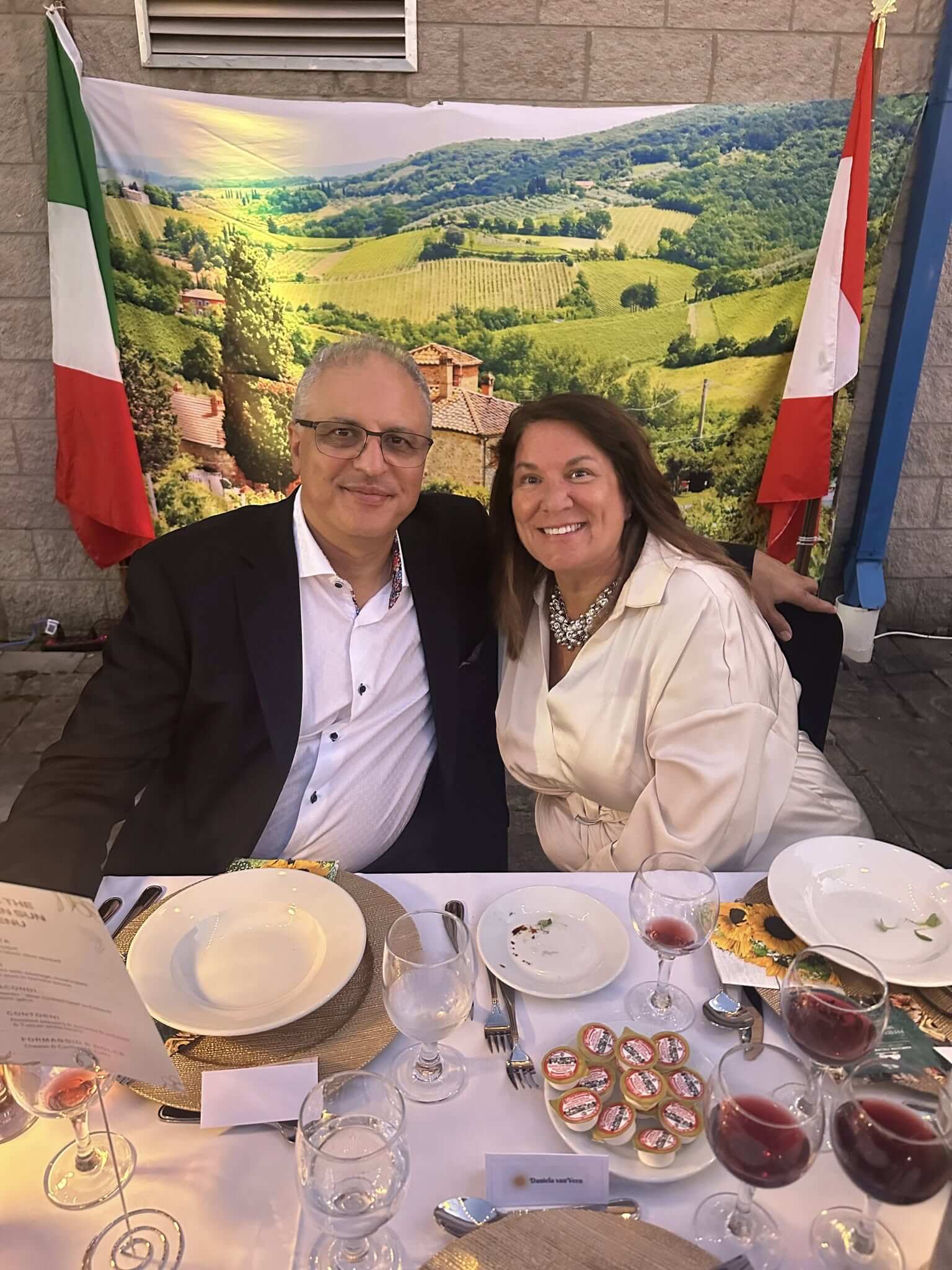 A smiling couple seated at a dining table with scenic backdrop.