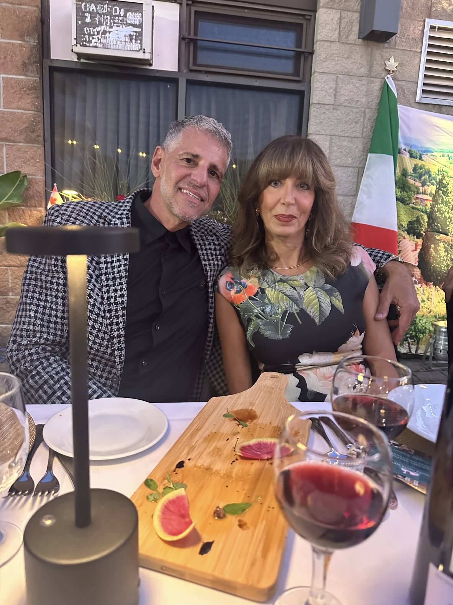 A couple enjoying a meal with wine outdoors at a restaurant.
