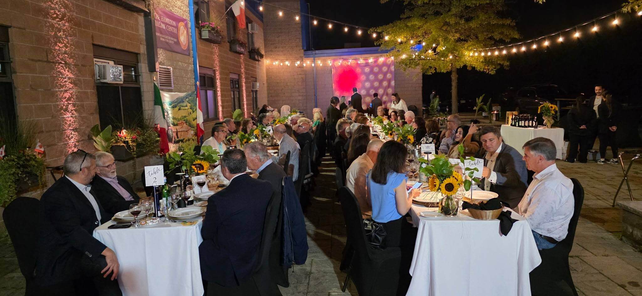 Elegant outdoor wedding reception with guests dining under string lights.