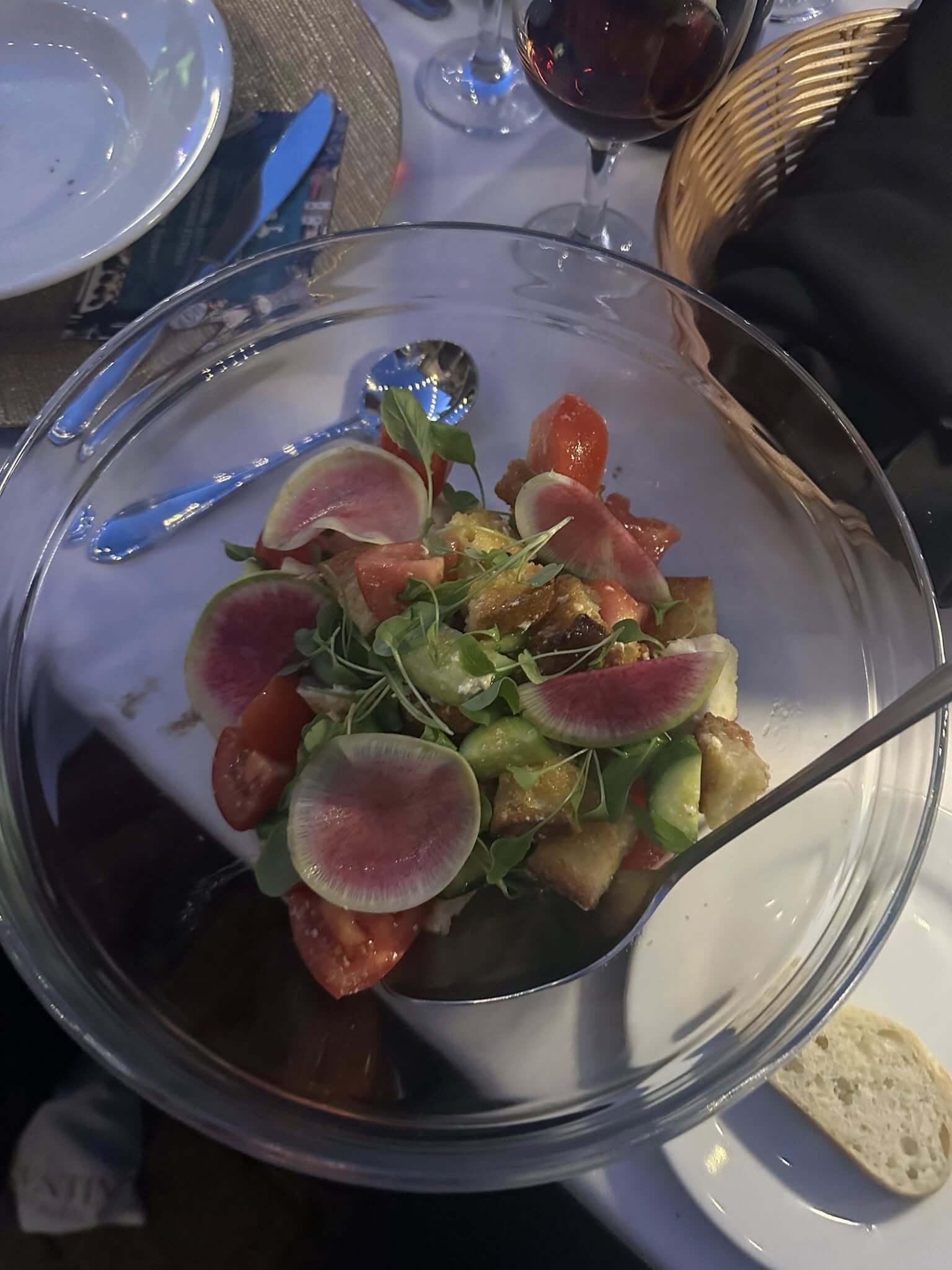 Fresh salad with watermelon radishes and greens in a glass bowl.