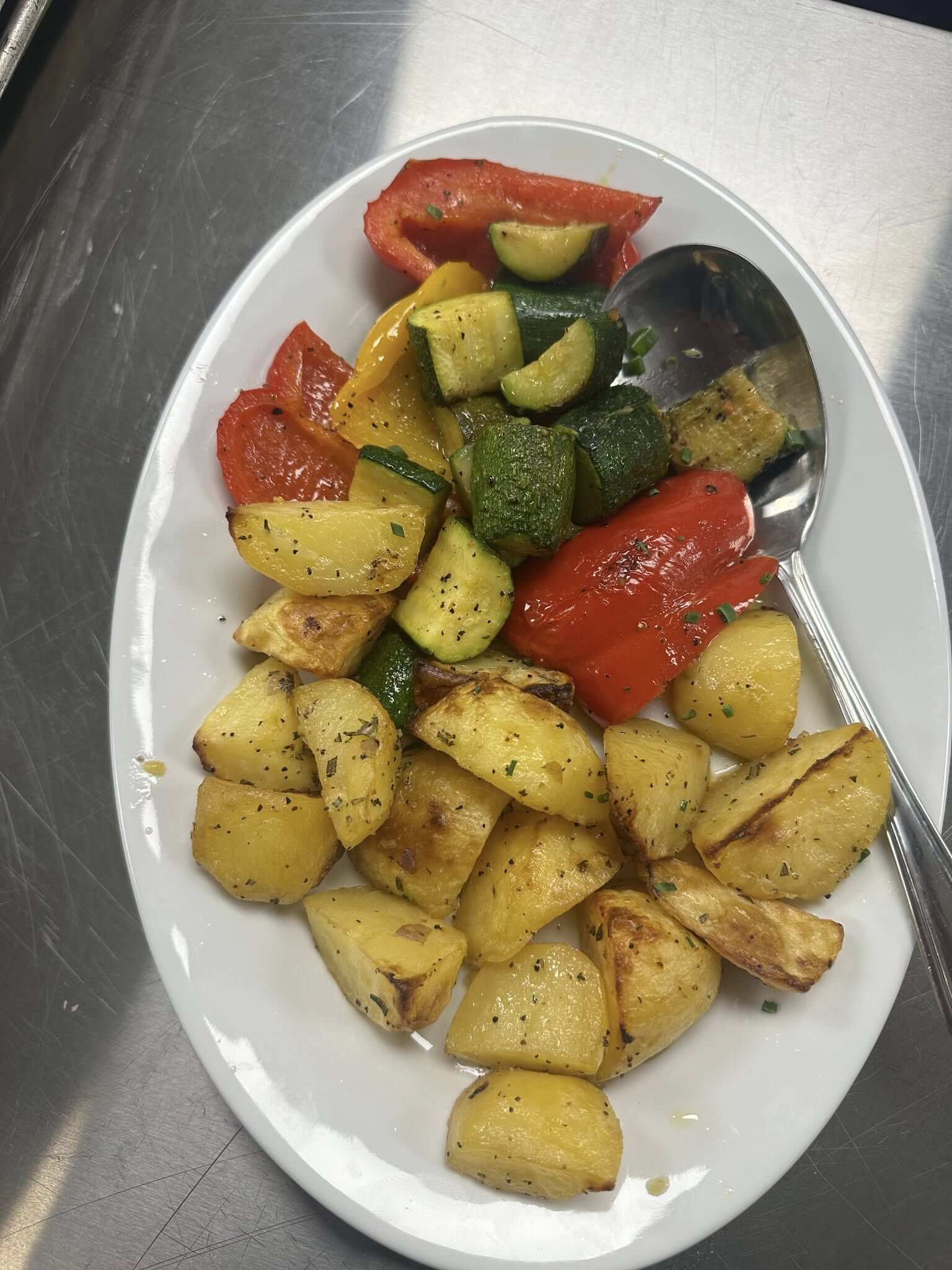 Roasted potatoes and mixed grilled vegetables on a white plate.