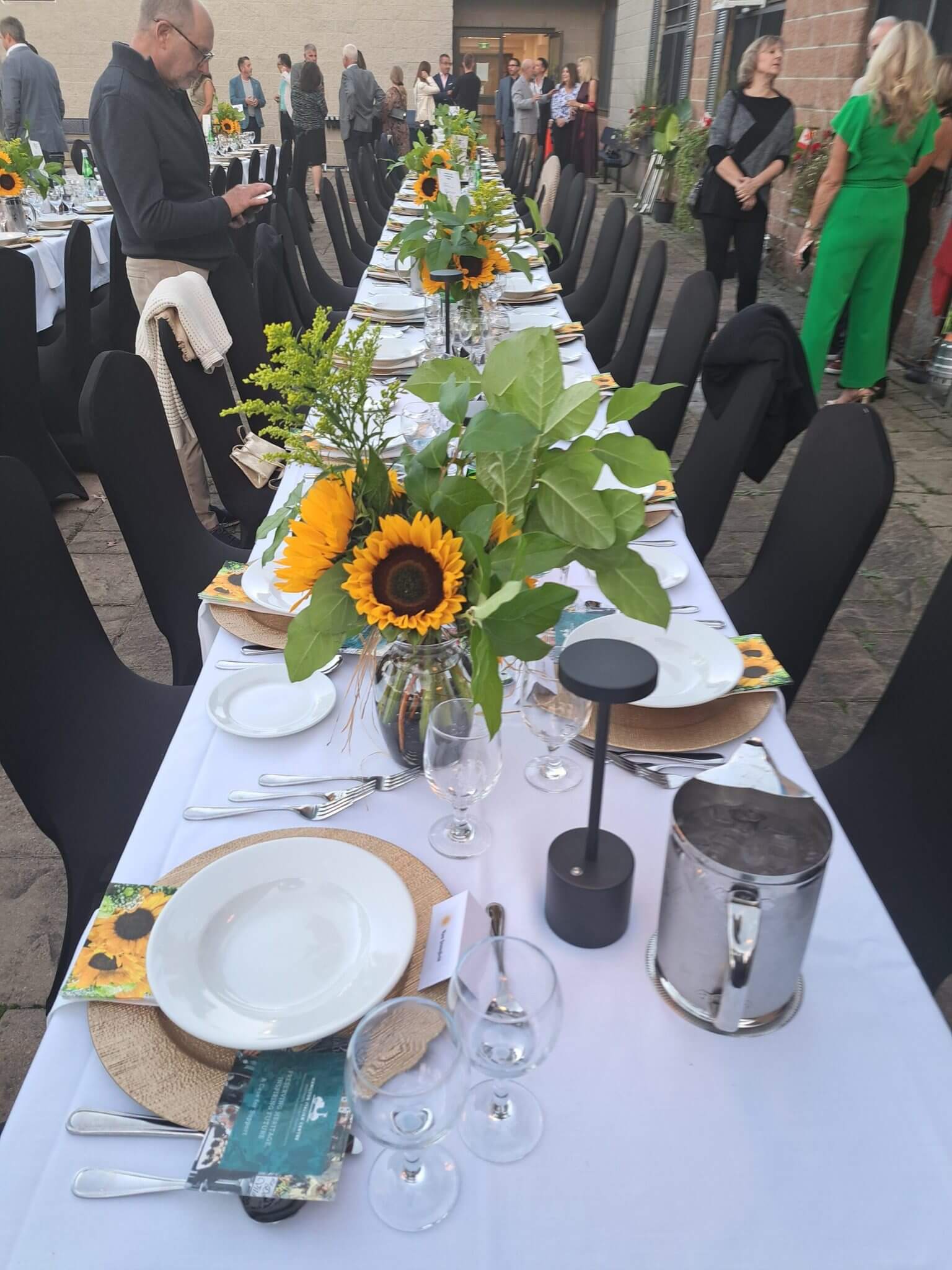 Elegant dining table with sunflower centerpiece and neatly arranged tableware.
