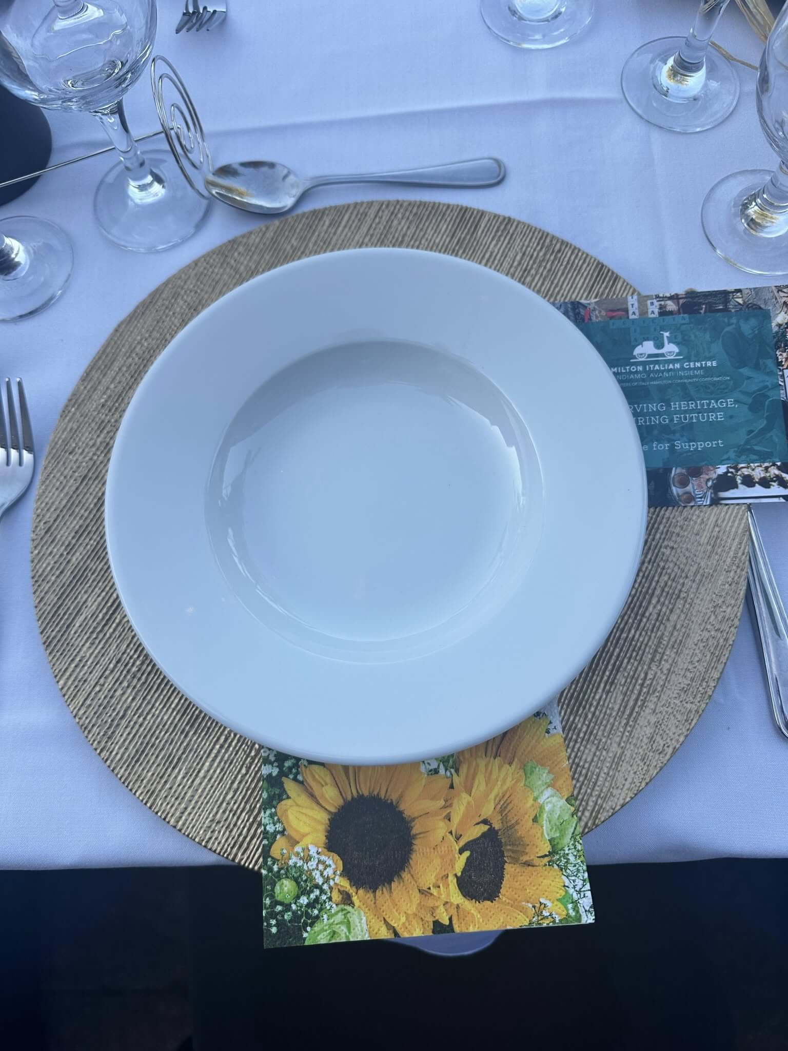 Empty white bowl on sunflower-themed placemat with silverware nearby.
