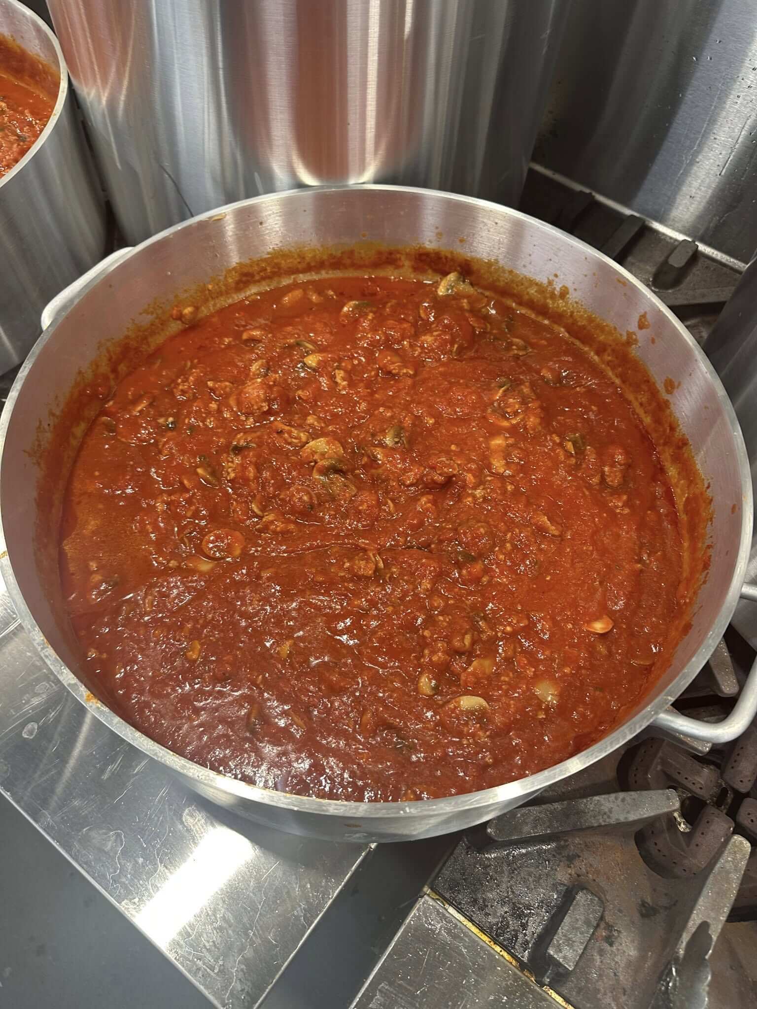 A large pot of rich, simmering tomato sauce with meat chunks.
