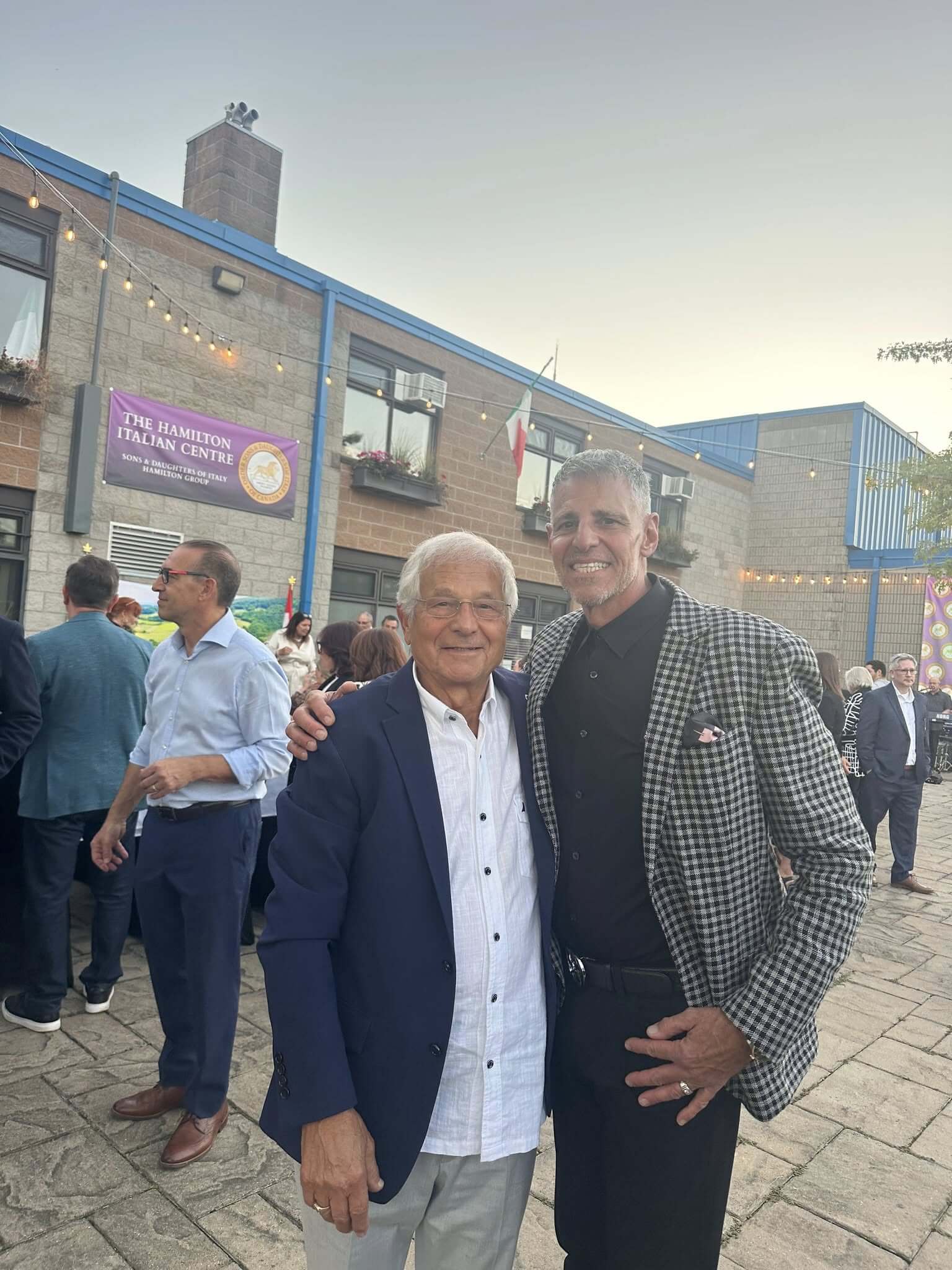 Two men smiling and posing together at an outdoor event.