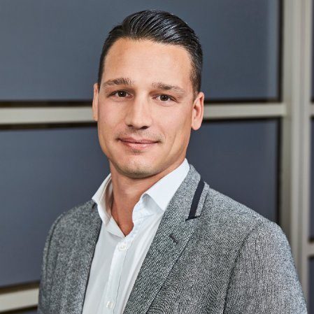 Professional man in a gray blazer and white shirt.