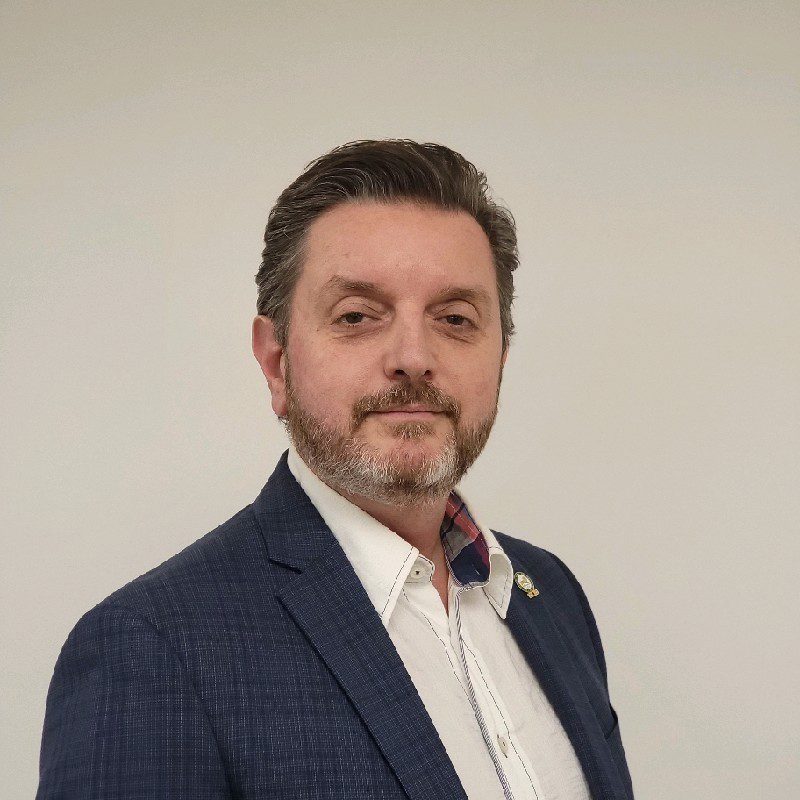 Professional man in a blue blazer against a plain background.