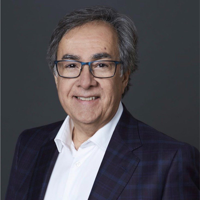 Middle-aged man in glasses and a blazer smiling.