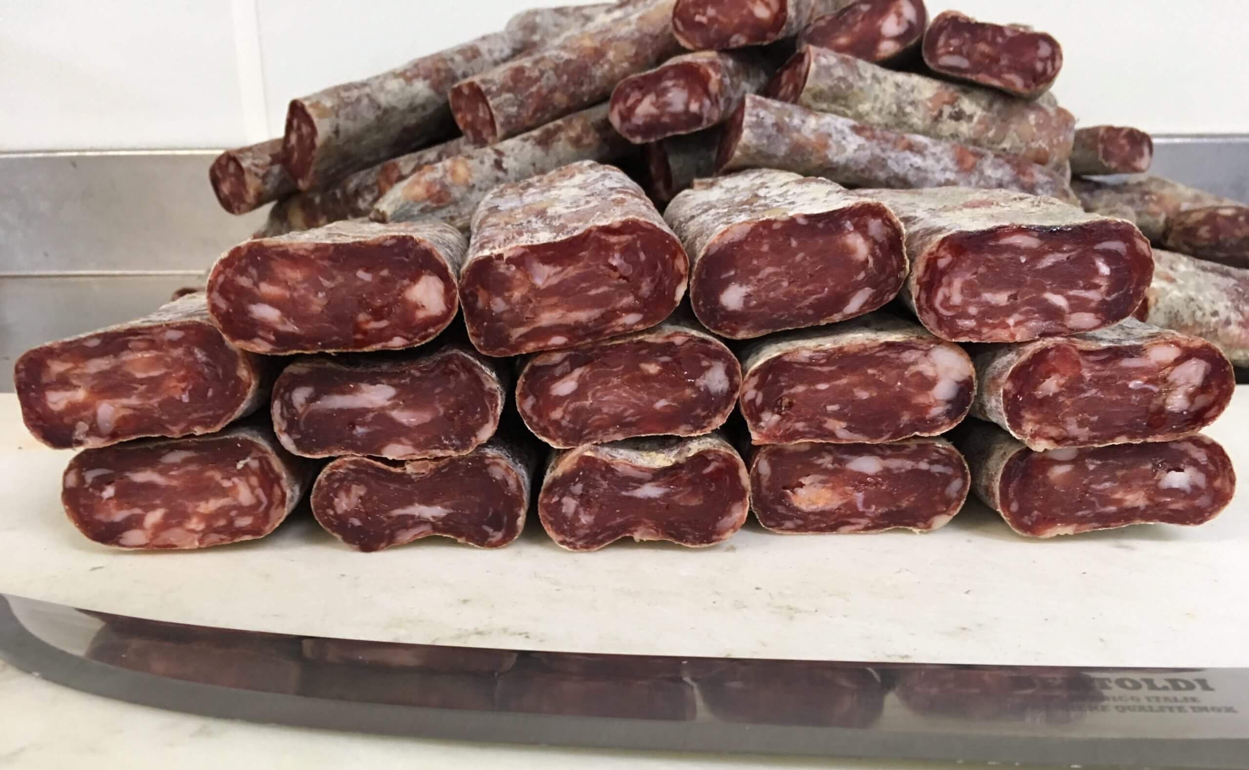 Stacked cured sausages on display table.