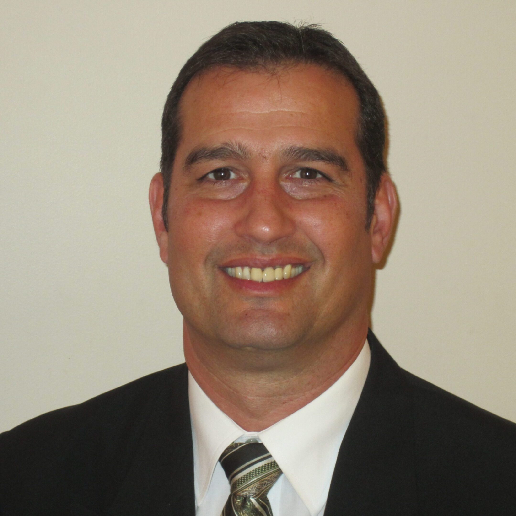 Smiling man in business attire against plain background.