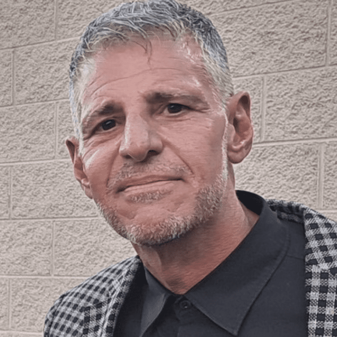 Portrait of a middle-aged man with short gray hair and a plaid jacket.