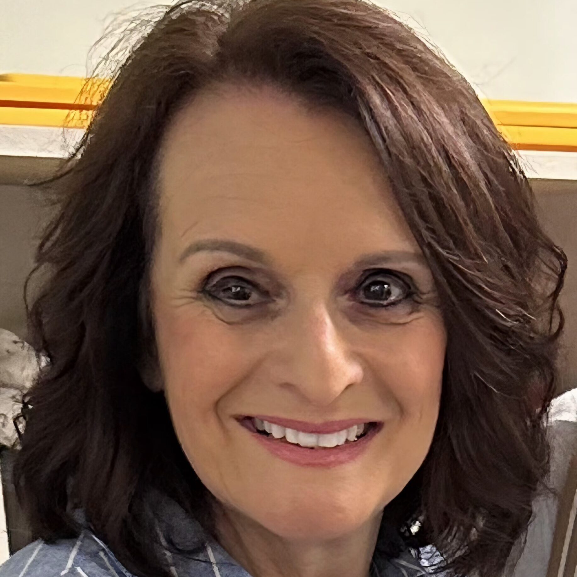 Smiling woman with wavy brown hair and warm eyes.